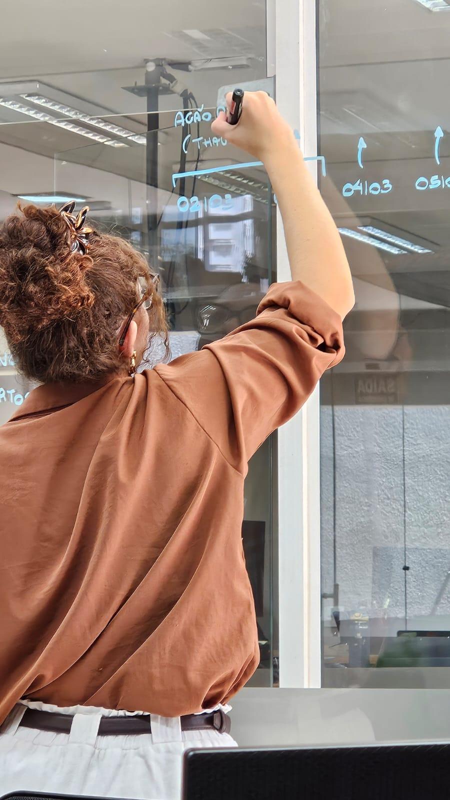 Gabrielle desenhando um fluxo no quadro de vidro